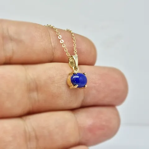 Dört tırnakla tutturulmuş oval lapis lazuli taşlı sarı altın kolye, el üzerinde